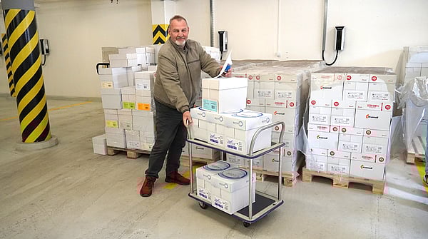 Mondi colleague next to several paper boxes, with a car full of paper for donation.