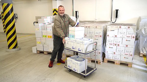 Mondi colleague next to several paper boxes, with a car full of paper for donation.