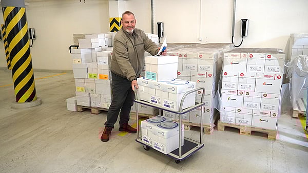 Mondi colleague next to several paper boxes, with a car full of paper for donation.
